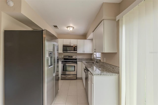 kitchen with light tile patterned floors, visible vents, appliances with stainless steel finishes, light stone counters, and a sink