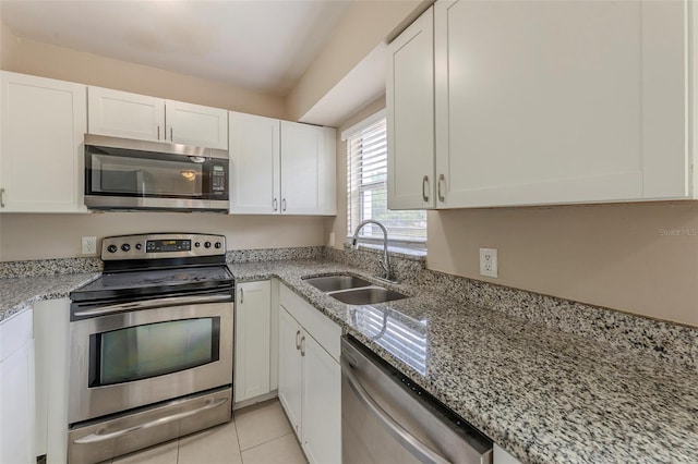 kitchen featuring light stone countertops, white cabinetry, light tile patterned flooring, a sink, and stainless steel appliances