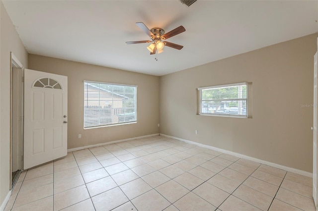 spare room with ceiling fan, baseboards, light tile patterned floors, and a wealth of natural light
