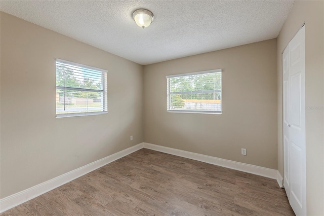 unfurnished room featuring baseboards, wood finished floors, and a textured ceiling
