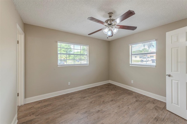 empty room featuring baseboards, light wood-style floors, and a textured ceiling