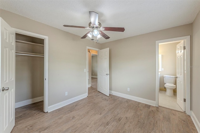 unfurnished bedroom with light wood-type flooring, a closet, baseboards, ensuite bathroom, and ceiling fan