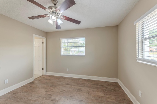 unfurnished room with plenty of natural light, a textured ceiling, and wood finished floors