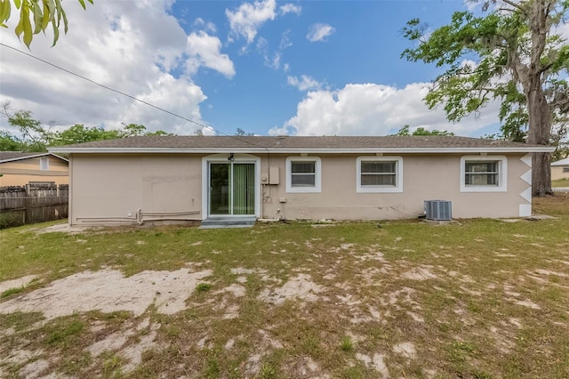 back of property with a yard, fence, central AC, and stucco siding