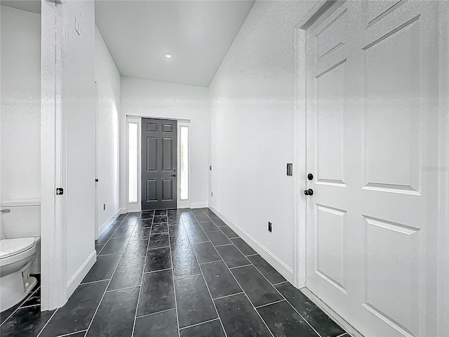 foyer entrance featuring baseboards and dark tile patterned flooring