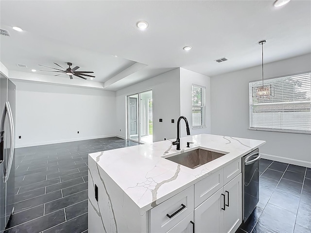 kitchen featuring ceiling fan with notable chandelier, light stone countertops, a tray ceiling, a sink, and stainless steel appliances