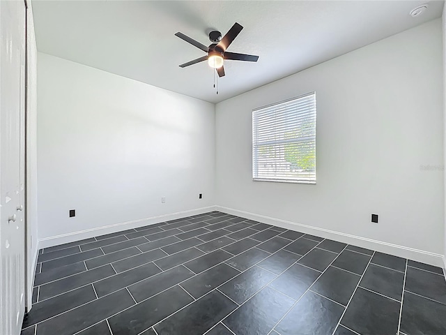 empty room featuring ceiling fan and baseboards