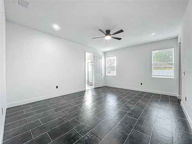 spare room with ceiling fan, baseboards, visible vents, and plenty of natural light