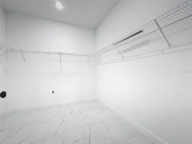 walk in closet featuring marble finish floor