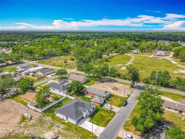 drone / aerial view featuring a wooded view and a residential view