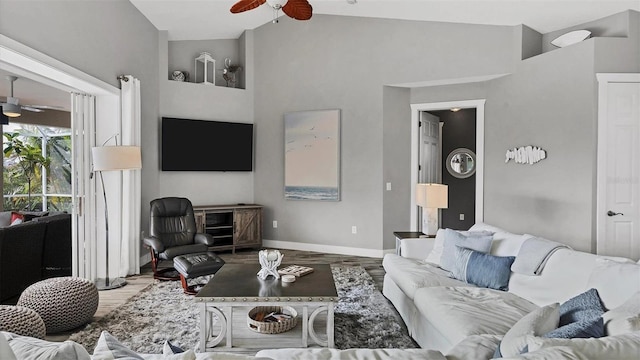 living area featuring high vaulted ceiling, baseboards, a ceiling fan, and wood finished floors