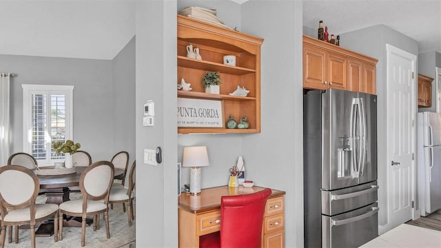 kitchen featuring stainless steel fridge with ice dispenser, open shelves, and freestanding refrigerator