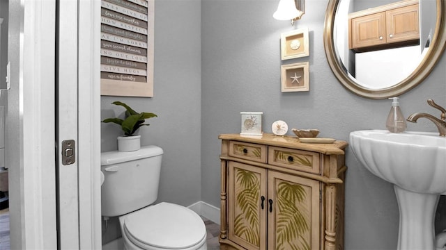 bathroom featuring baseboards, a sink, and toilet