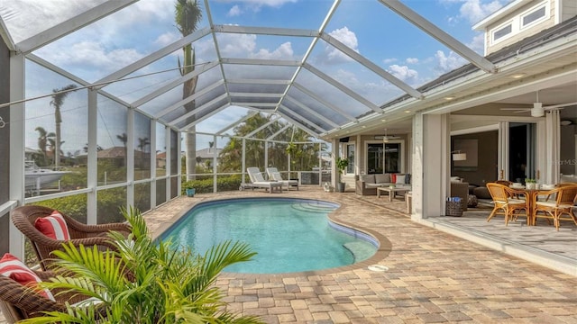 pool with a lanai, a patio area, outdoor lounge area, and a ceiling fan