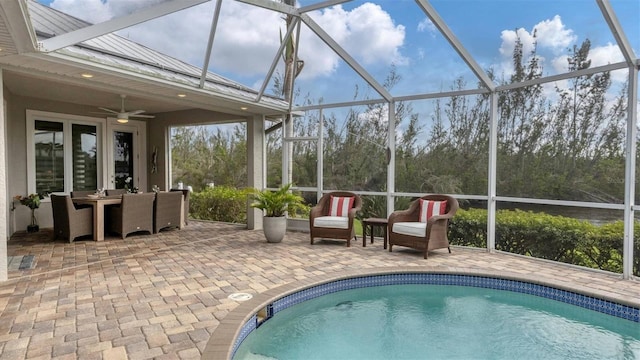 outdoor pool with a patio area, glass enclosure, and ceiling fan
