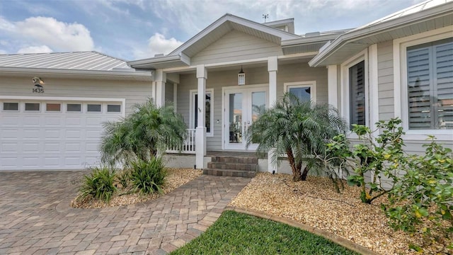 property entrance with an attached garage, french doors, covered porch, and decorative driveway