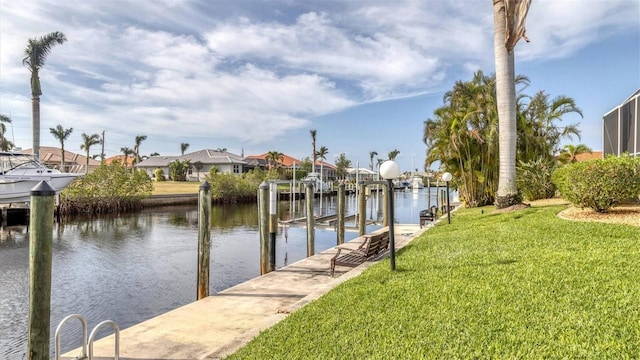 view of dock with boat lift, a yard, a residential view, and a water view