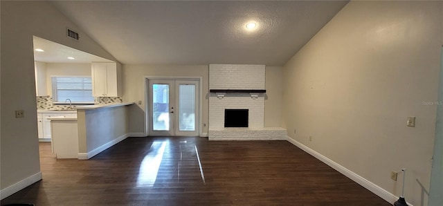 unfurnished living room with a sink, visible vents, baseboards, vaulted ceiling, and dark wood-type flooring