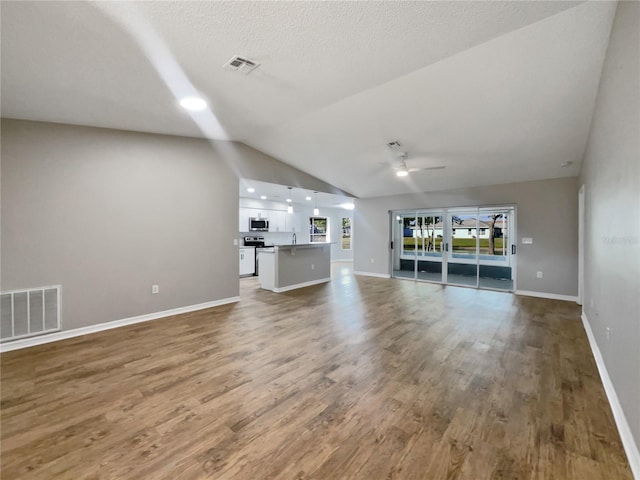 unfurnished living room featuring visible vents, a ceiling fan, wood finished floors, and lofted ceiling