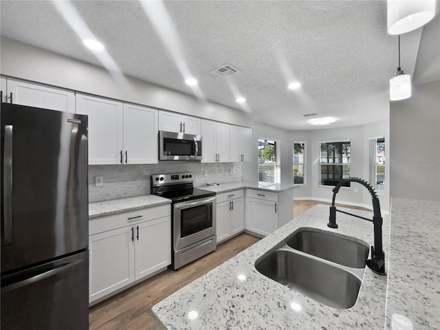 kitchen featuring white cabinetry, visible vents, decorative backsplash, stainless steel appliances, and a sink