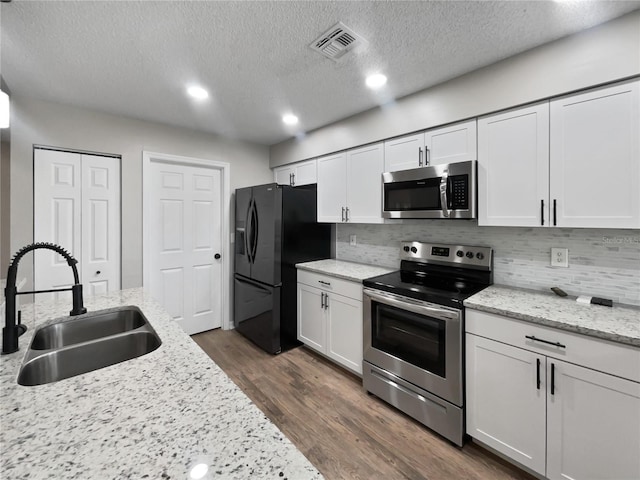 kitchen featuring visible vents, a sink, appliances with stainless steel finishes, dark wood-style floors, and white cabinetry
