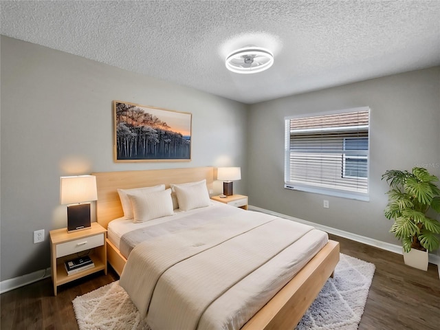 bedroom featuring baseboards, a textured ceiling, and dark wood-style floors
