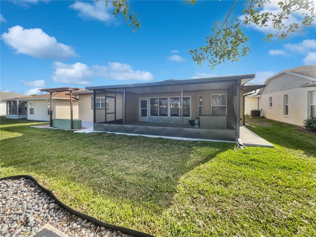 rear view of house with a yard, central AC, a sunroom, and stucco siding