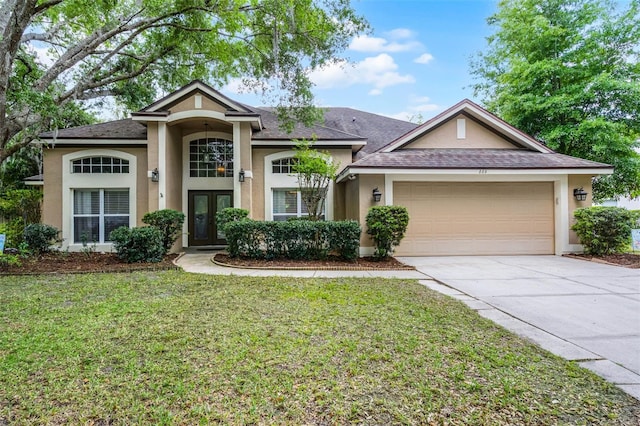 view of front of property with stucco siding, driveway, french doors, an attached garage, and a front yard