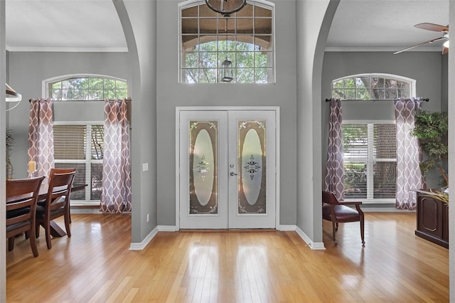 foyer with ornamental molding, arched walkways, and plenty of natural light