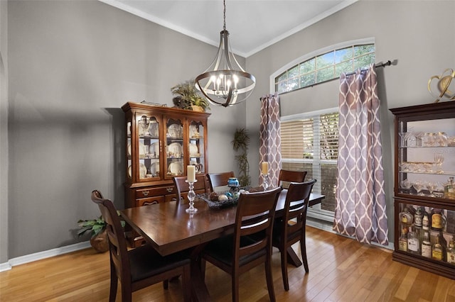 dining area featuring wood finished floors, a notable chandelier, ornamental molding, and a towering ceiling