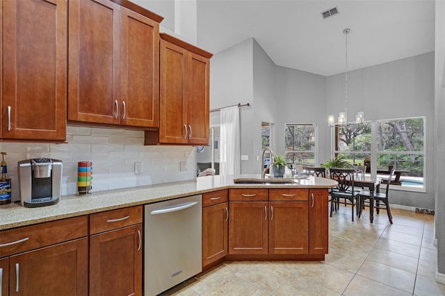 kitchen featuring a high ceiling, visible vents, brown cabinets, stainless steel dishwasher, and a sink