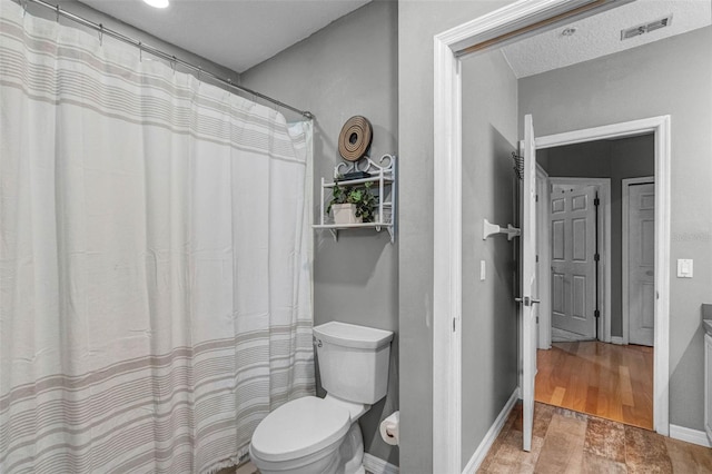 bathroom featuring toilet, a shower with curtain, baseboards, and visible vents