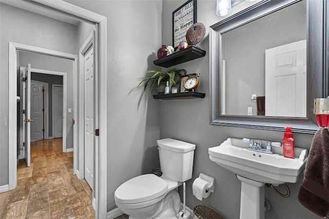bathroom featuring toilet, stone finish floor, and baseboards