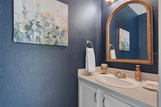 bathroom with a textured wall and vanity