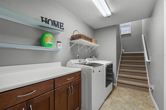 washroom featuring a textured ceiling, laundry area, baseboards, and washing machine and dryer