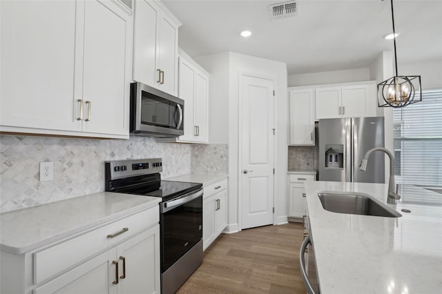 16484 Silver Brook Way, Winter Garden, FL 34787 - kitchen featuring appliances with stainless steel finishes, a sink, wood finished floors, white cabinets, and light stone counters