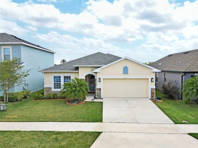 view of front of house featuring stucco siding, a front yard, stone siding, an attached garage, and concrete driveway