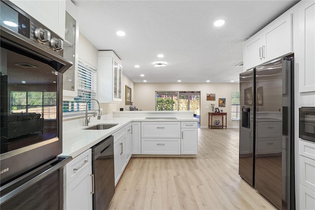 110 Tedworth Ct, Longwood, FL 32779 - kitchen featuring appliances with stainless steel finishes, a sink, light wood-type flooring, a peninsula, and glass insert cabinets