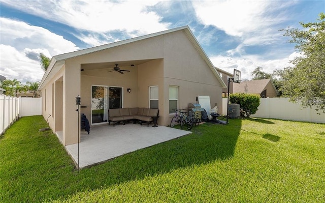 rear view of house with stucco siding, ceiling fan, a yard, and a fenced backyard