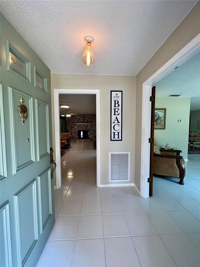 3652 Oak Grove Dr, Sarasota, FL 34243 - entryway featuring a textured ceiling, light tile patterned floors, a stone fireplace, and baseboards