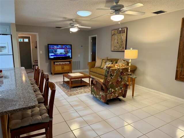 3652 Oak Grove Dr, Sarasota, FL 34243 - living area featuring a ceiling fan, a textured ceiling, baseboards, and light tile patterned floors