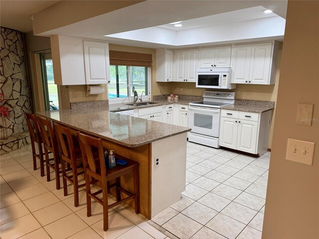 3652 Oak Grove Dr, Sarasota, FL 34243 - kitchen with white appliances, light tile patterned floors, a sink, a raised ceiling, and recessed lighting
