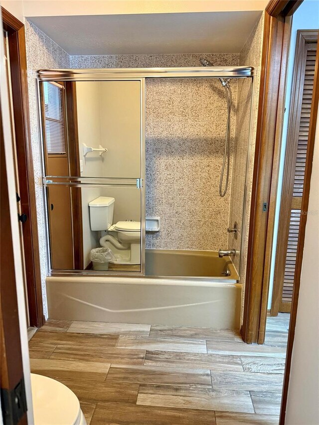 3652 Oak Grove Dr, Sarasota, FL 34243 - bathroom with toilet, wood finished floors, and combined bath / shower with glass door