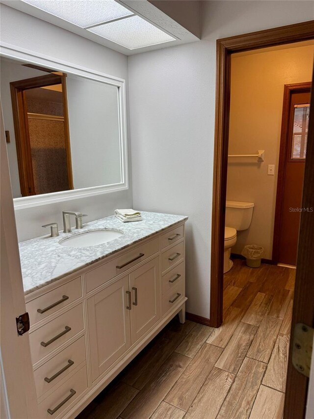 3652 Oak Grove Dr, Sarasota, FL 34243 - bathroom with wood finished floors, vanity, toilet, and baseboards