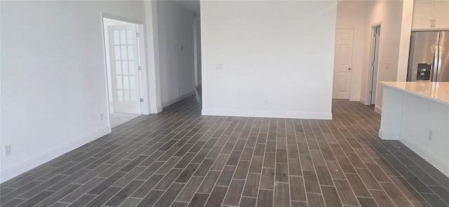 unfurnished living room with dark wood-style floors and baseboards