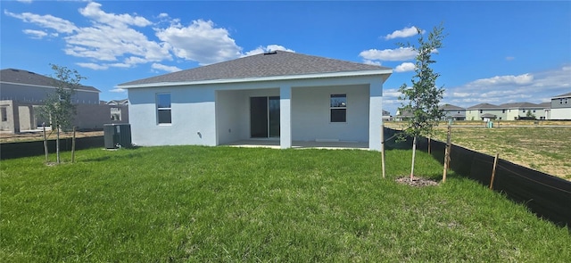 back of property featuring stucco siding, a patio area, central AC, a fenced backyard, and a yard