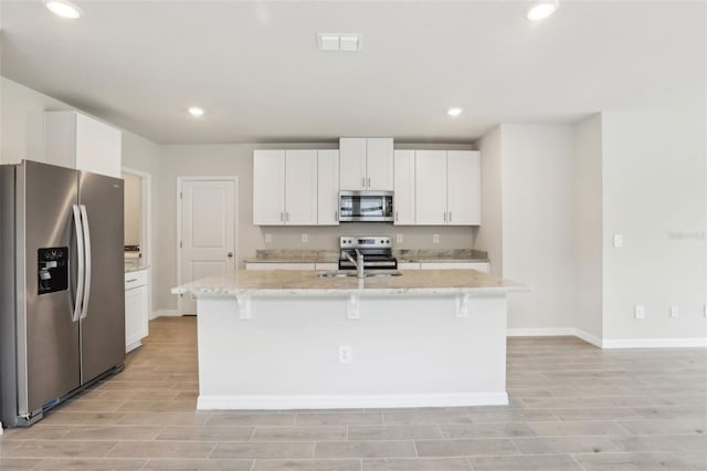 2320 E Newsome Rd, Plant City, FL 33565 - kitchen with an island with sink, appliances with stainless steel finishes, baseboards, white cabinetry, and visible vents