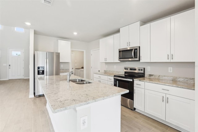 2320 E Newsome Rd, Plant City, FL 33565 - kitchen with white cabinets, a sink, light wood-style floors, a center island with sink, and appliances with stainless steel finishes