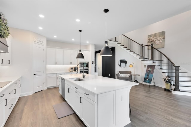 14749 Walcott Ave, Orlando, FL 32827 - kitchen featuring light countertops, a kitchen island with sink, light wood-style floors, stainless steel appliances, and a sink