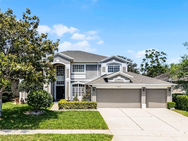 10033 Hart Branch Cir, Orlando, FL 32832 - traditional-style house featuring stucco siding, a garage, driveway, a front lawn, and roof with shingles